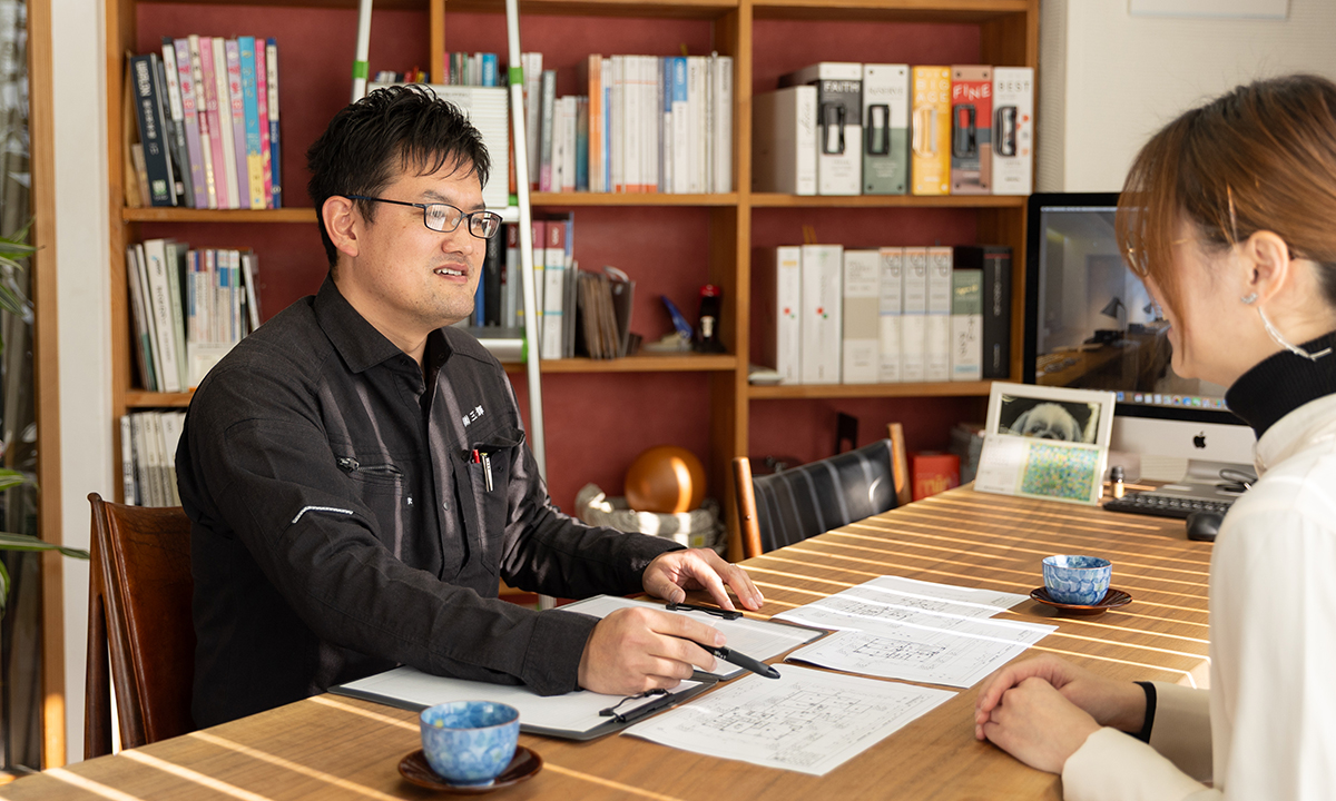 建材カタログを確認しながら話し合う2人の社員